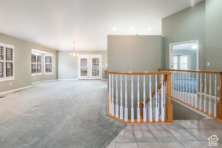 Open floor plan featuring a staircase with wood handrails and white balusters, recessed lighting, multi-pane glass doors, and window shutters