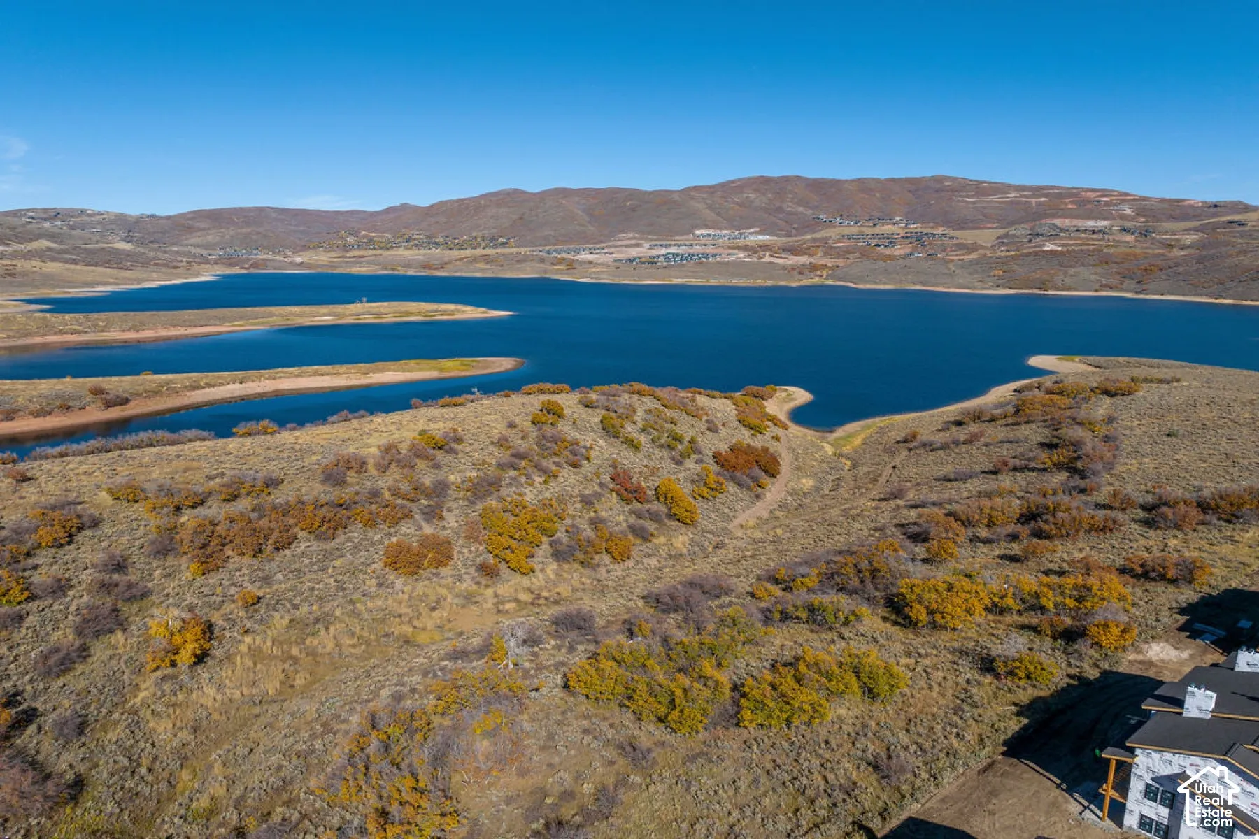 Expansive water body, surrounding hills, and visible new construction