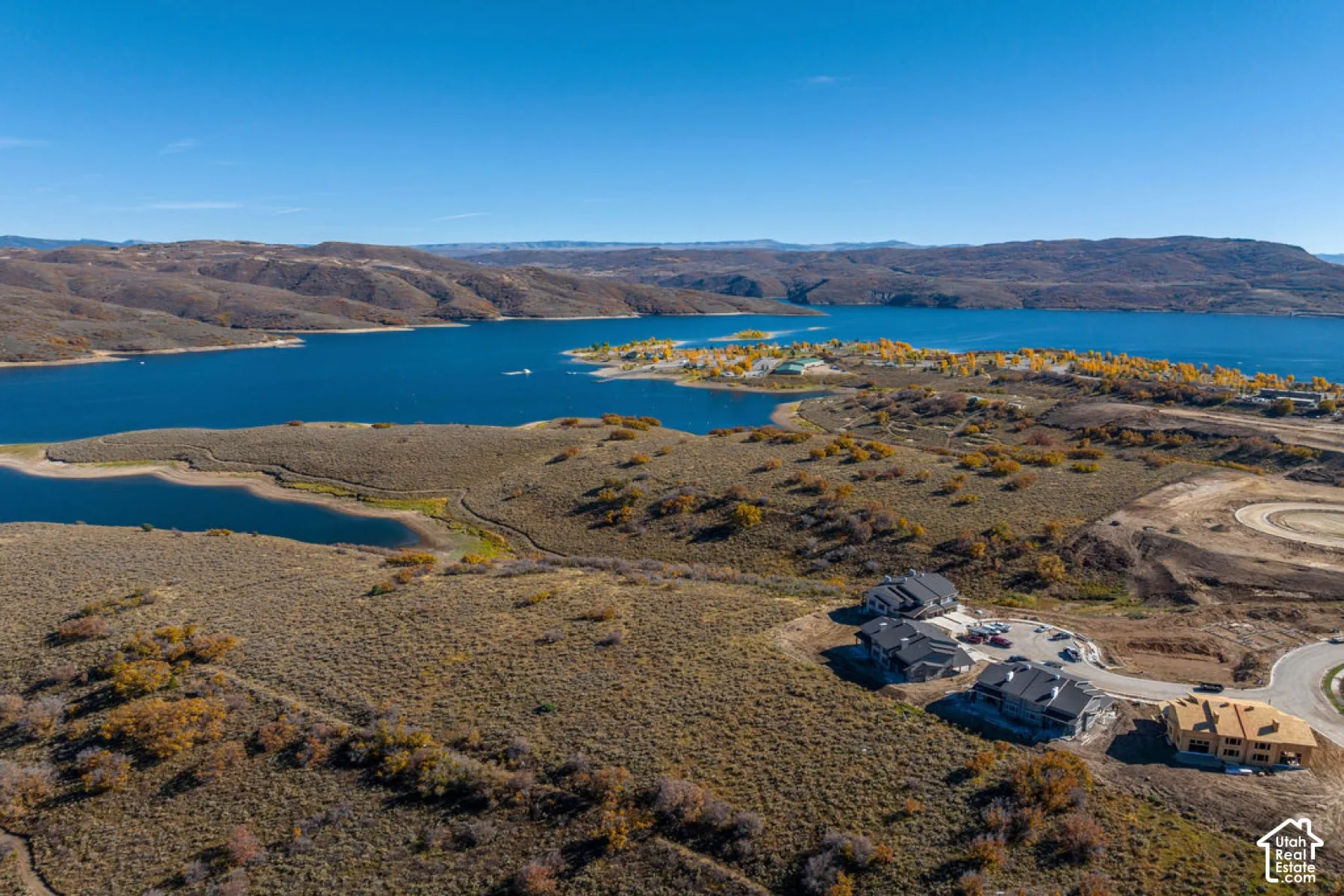 Expansive waterfront property with surrounding hills, a large body of water, and developing residential sites