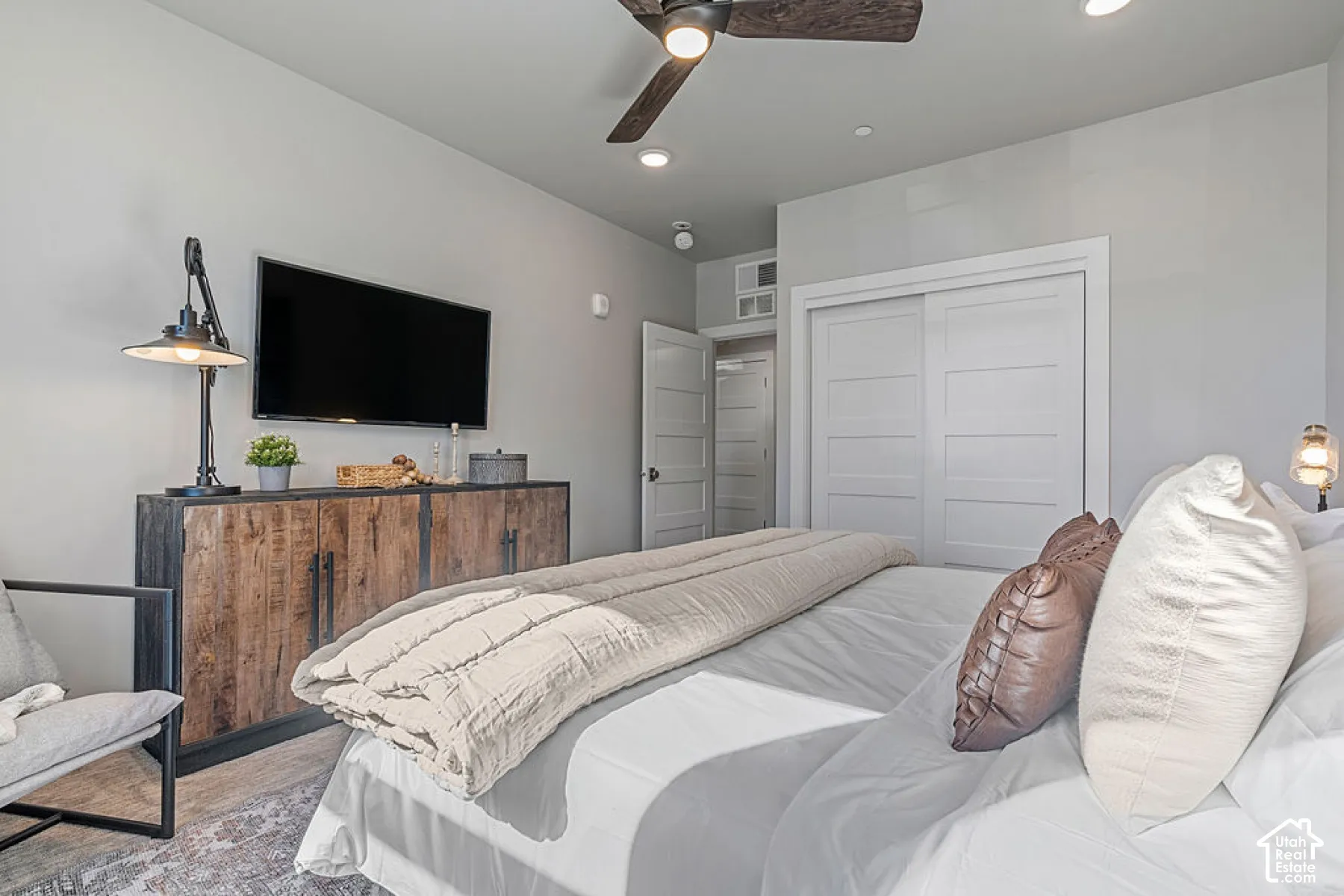 Integrated ceiling fan, recessed lighting, wood-finish flooring, sliding panel closet doors, and built-in storage console