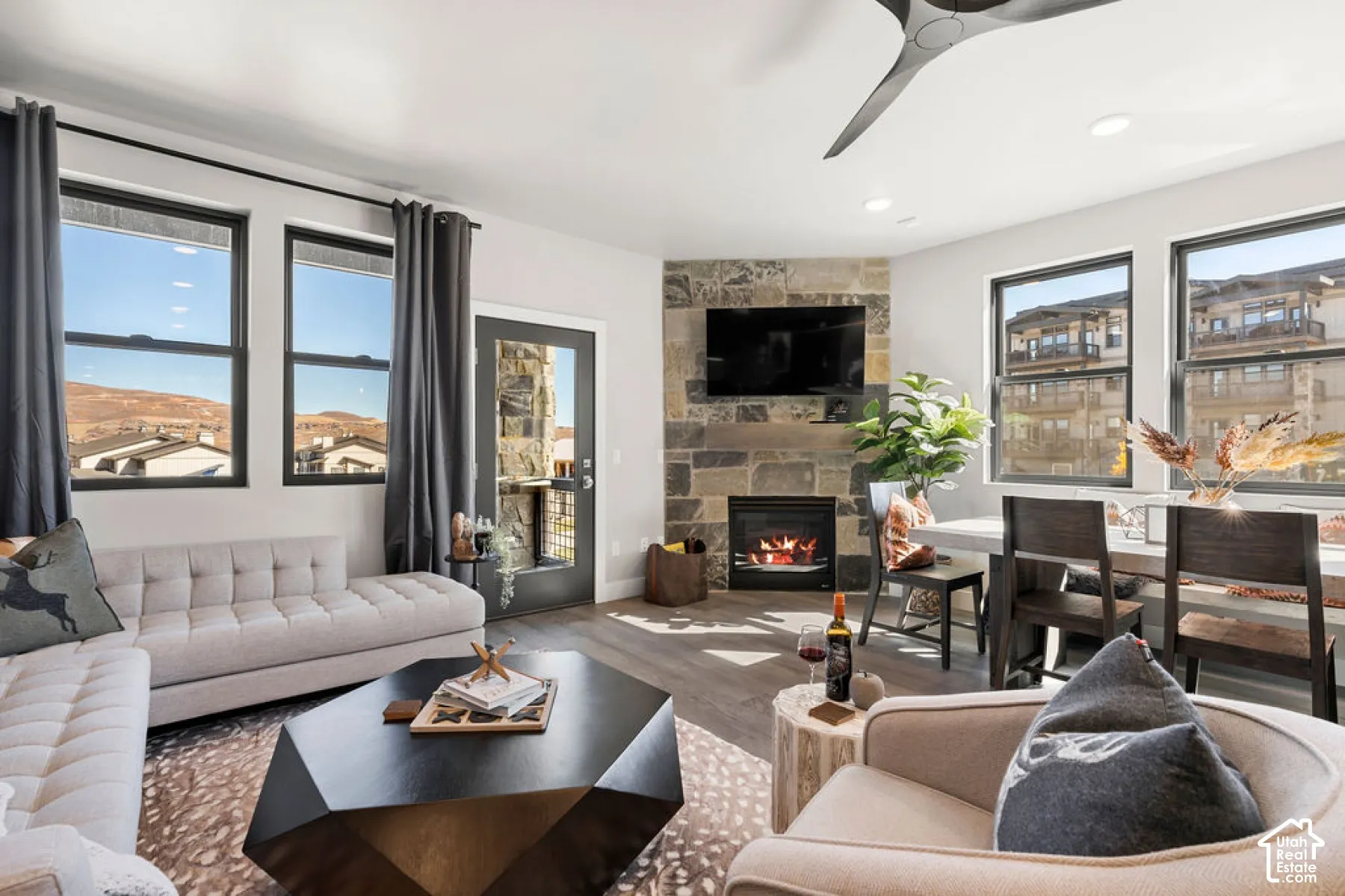 Living space featuring a stone-clad fireplace, wood-finish flooring, recessed lighting, and multiple windows