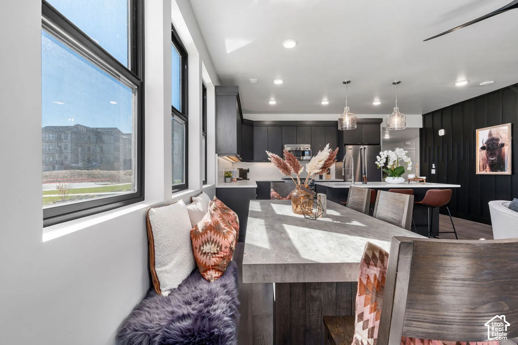Integrated dining area with window seating, wood-finish flooring, recessed lighting, and pendant fixtures