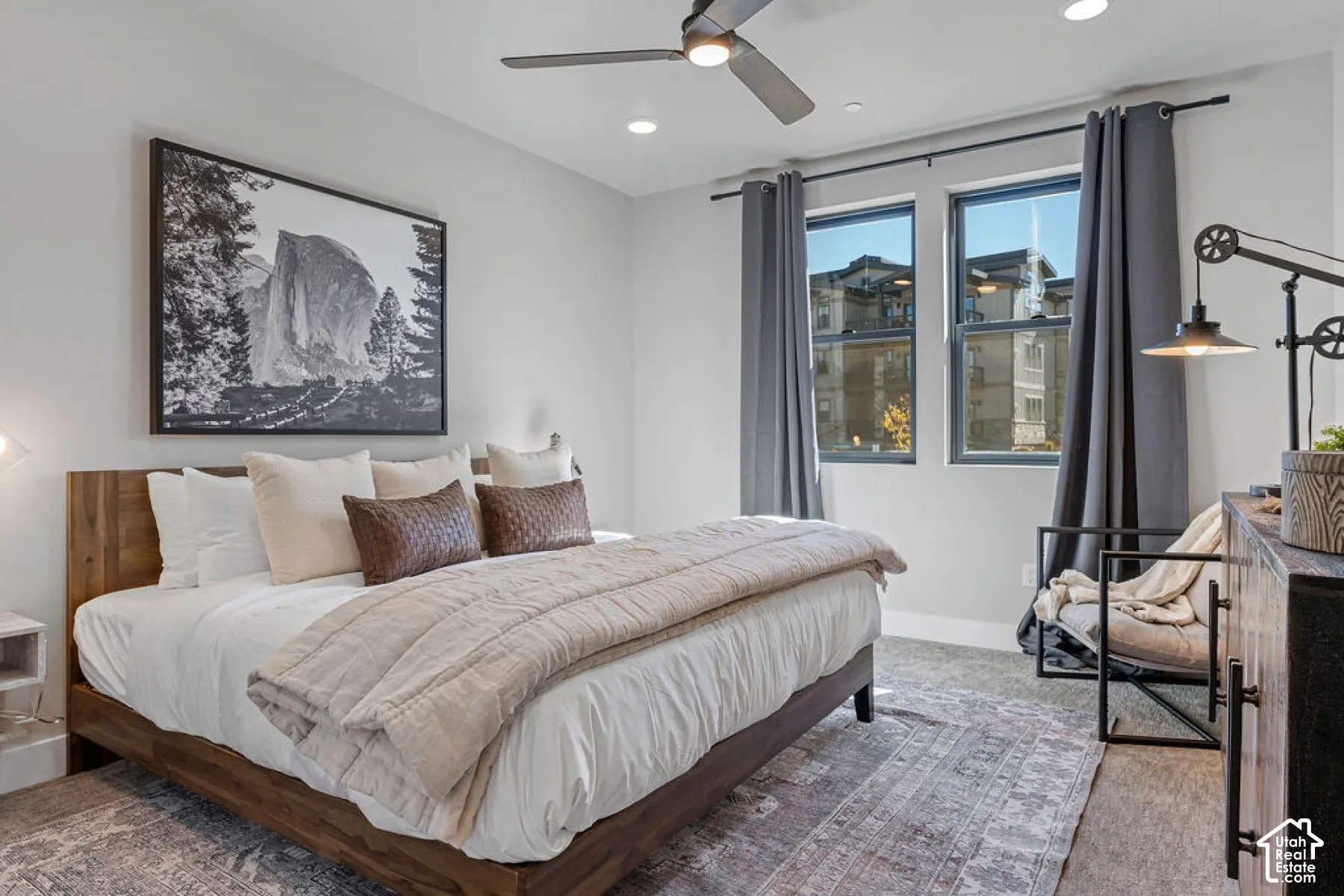Recessed lighting, ceiling fan, two large windows, dark gray window treatments, and light gray wall paint