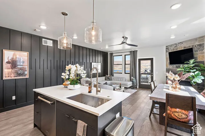 Kitchen island with integrated stainless steel sink and appliance, white countertop, and pendant lighting