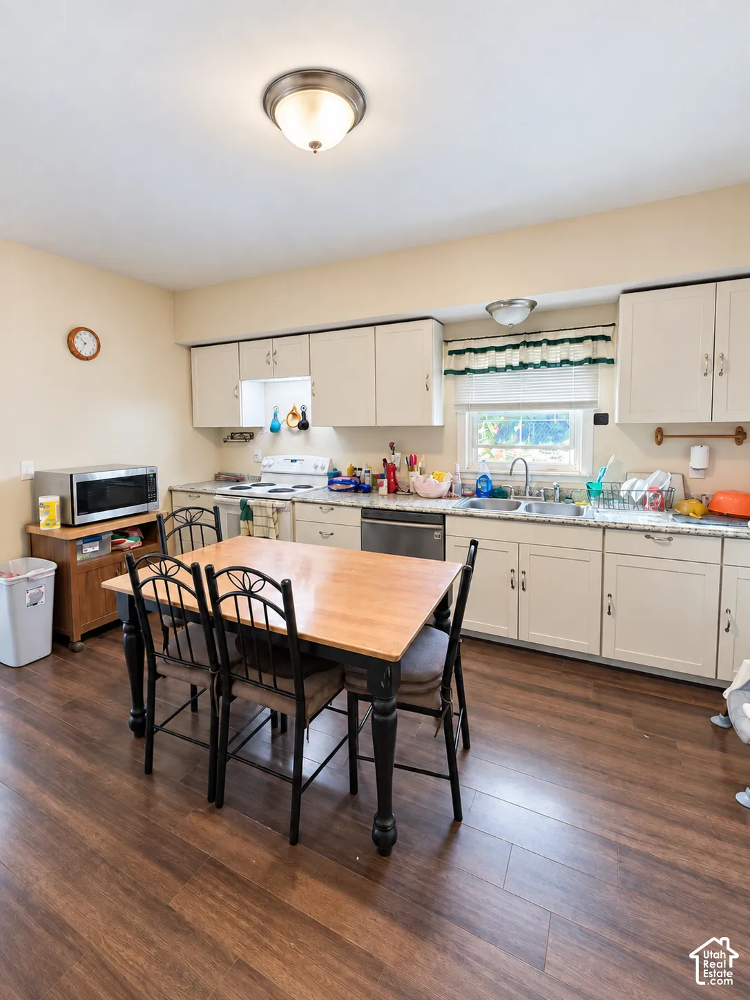 Kitchen featuring wood-finish flooring, white cabinetry, a built-in dishwasher, and a double basin sink