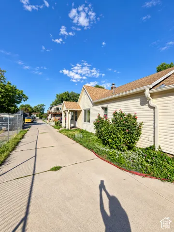 Charming residential property featuring a light-colored exterior with pitched roof and clay tile accents, complemented by mature landscaping along the front walkway