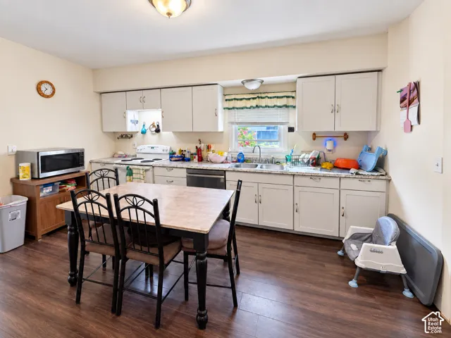 Kitchen featuring wood-finish flooring, light cabinetry, a double basin sink, and ample countertop space