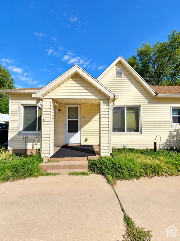 Exterior siding with an integrated porch, featuring a white entry door and white-framed windows