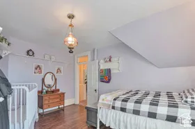 Vaulted ceiling with a decorative pendant light, wood-finish flooring, and white interior door