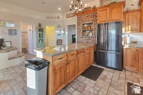 Kitchen featuring wood cabinetry, a center island with a stone-finish countertop, a built-in refrigerator, and tile flooring