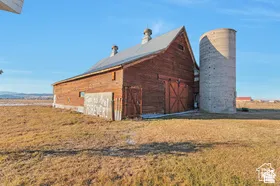 Barn structure with red wood siding, a metal roof, and a cupola