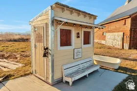 Detached utility structure with horizontal siding and a corrugated metal roof