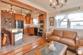 Exposed wood beam, brick accent wall, wood-finish cabinetry, tile flooring, and double-pane windows