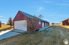 Red barn structure with a gray metal roof, single garage door, and multiple individual stalls