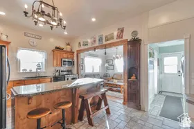 Kitchen featuring wood cabinetry, stainless steel appliances, granite-look countertops, a central island with seating, and tile flooring