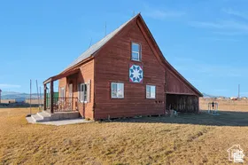 Barn-style residence featuring a prominent gable roof, red siding, and white-trimmed windows