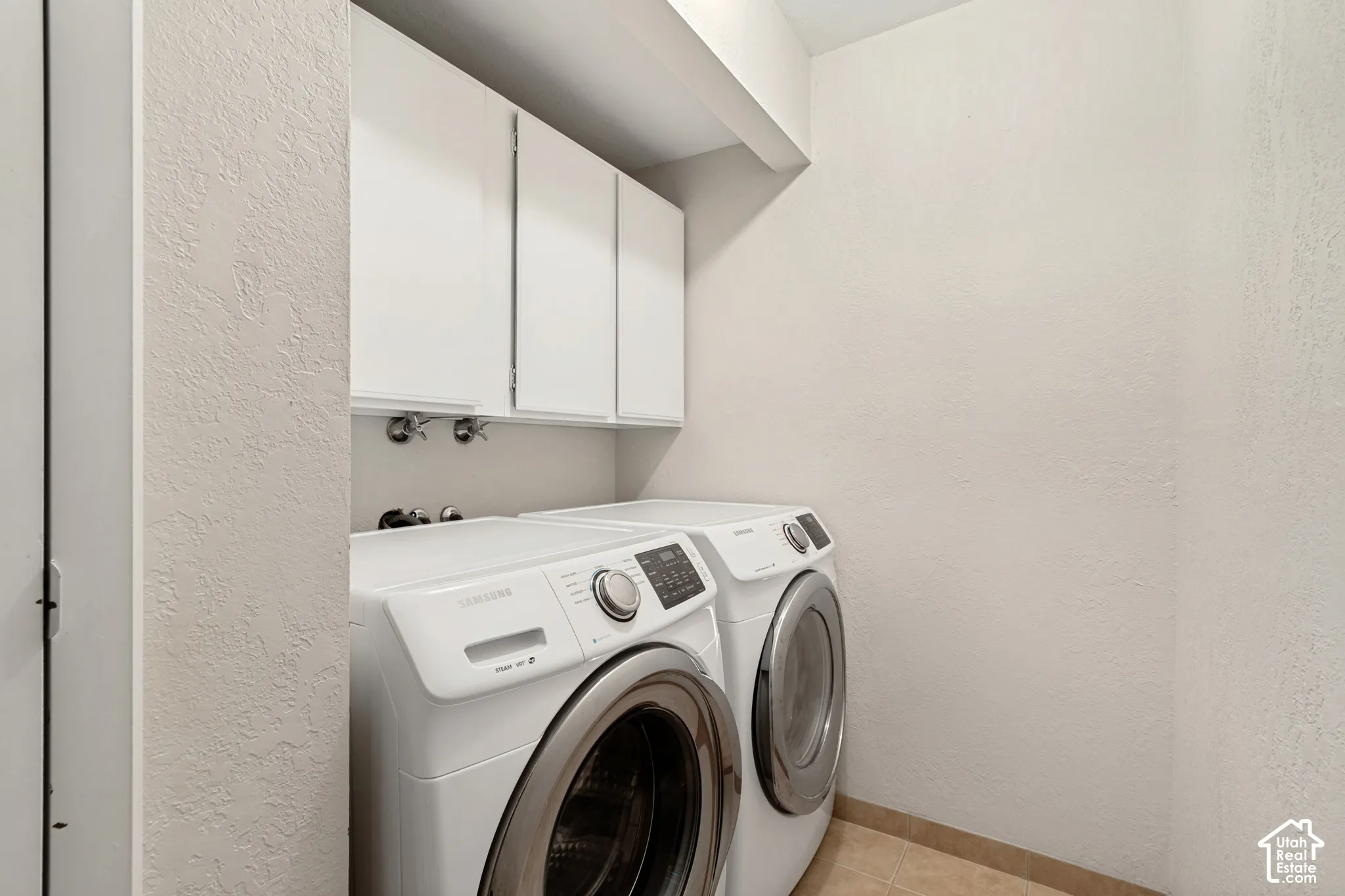 Built-in overhead white cabinetry, and light-toned floor tiling