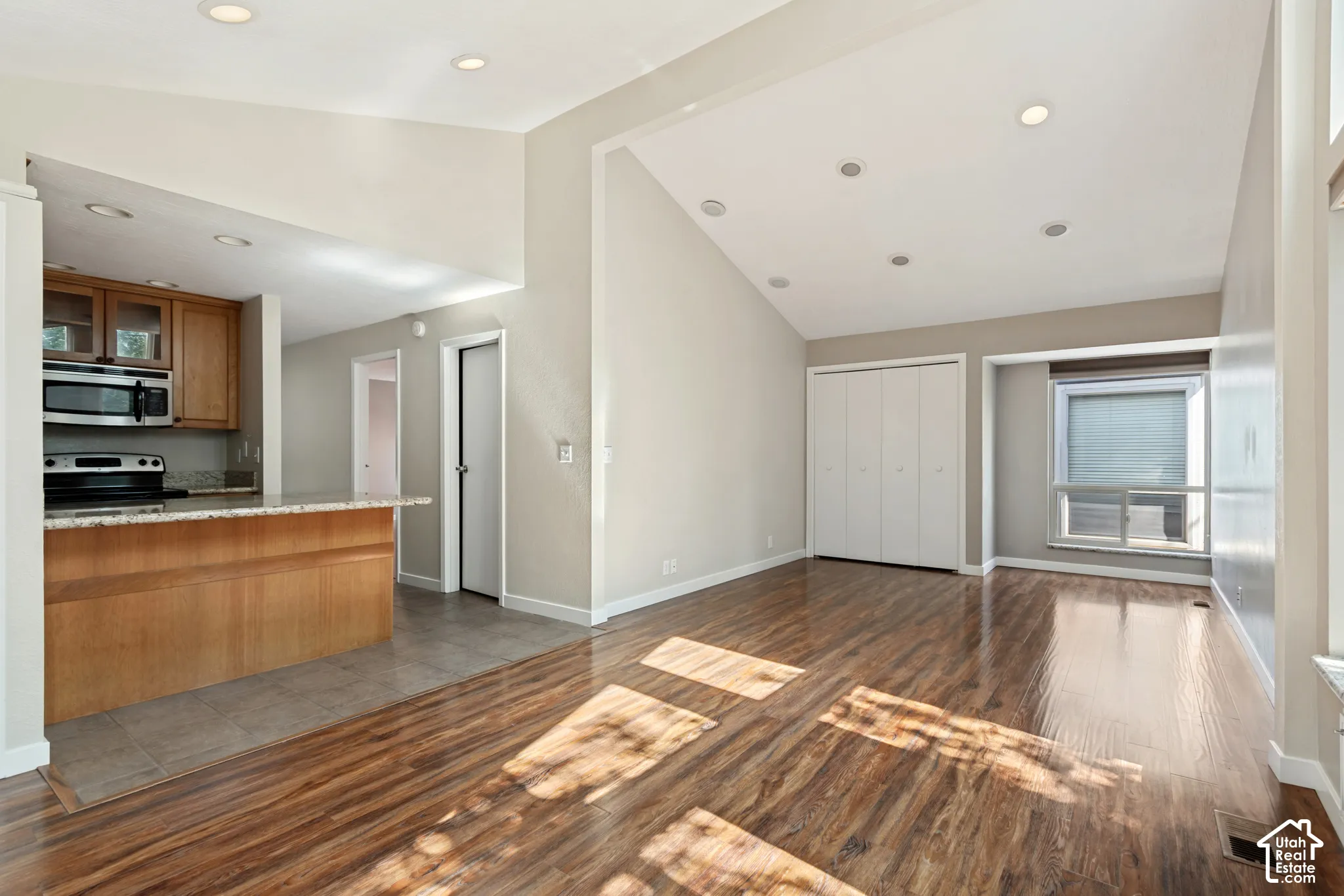 Open-concept living space featuring rich wood-finish flooring throughout, recessed ceiling lighting, and abundant natural light from multiple windows