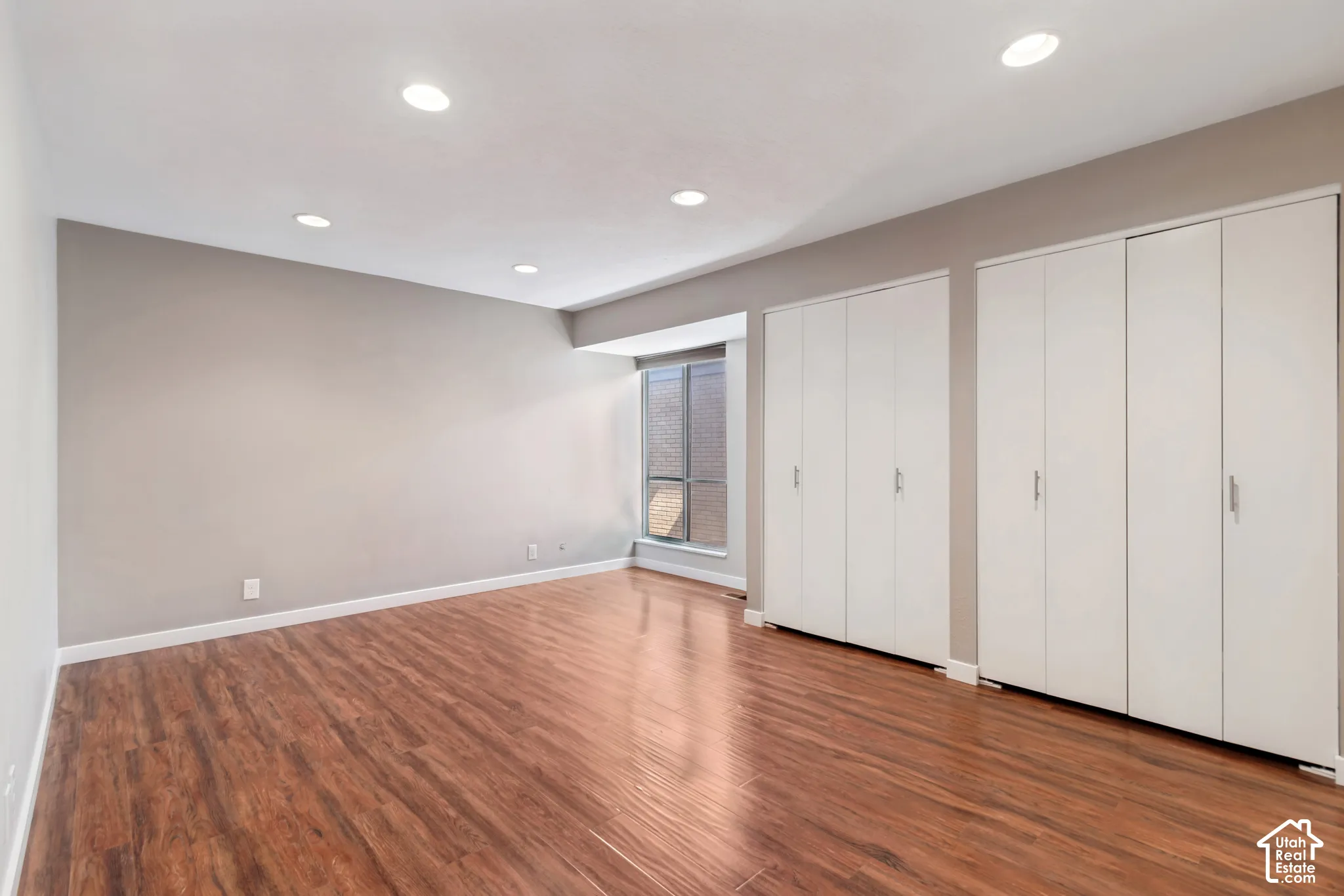 Recessed lighting illuminates the wood-finish flooring and neutral wall tones