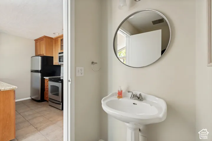 Pedestal sink with chrome faucet, circular mirror, and hardwood cabinetry visible from doorway