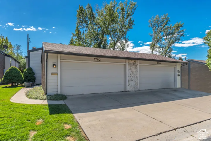 Two-car garage with white garage doors, stone veneer accents, and exterior wall sconces