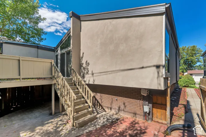 Stucco exterior with extensive window lines, elevated wood deck, and wood staircase