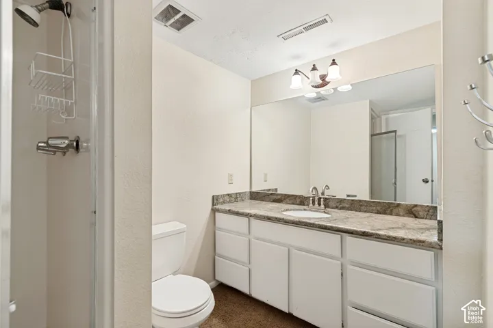 White vanity with ample cabinet storage, undermount sink, and a stone countertop