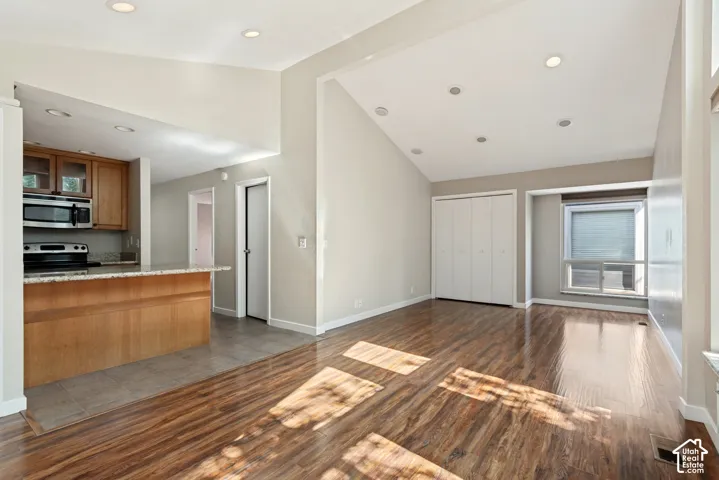 Open-concept living space featuring rich wood-finish flooring throughout, recessed ceiling lighting, and abundant natural light from multiple windows
