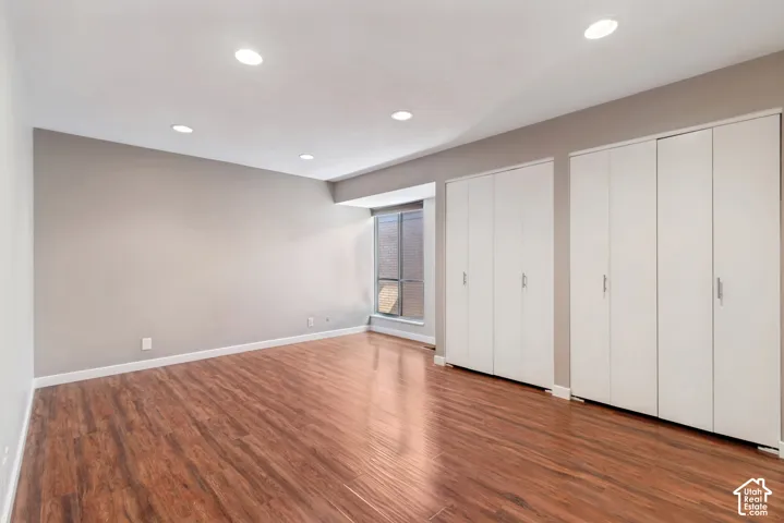 Recessed lighting illuminates the wood-finish flooring and neutral wall tones