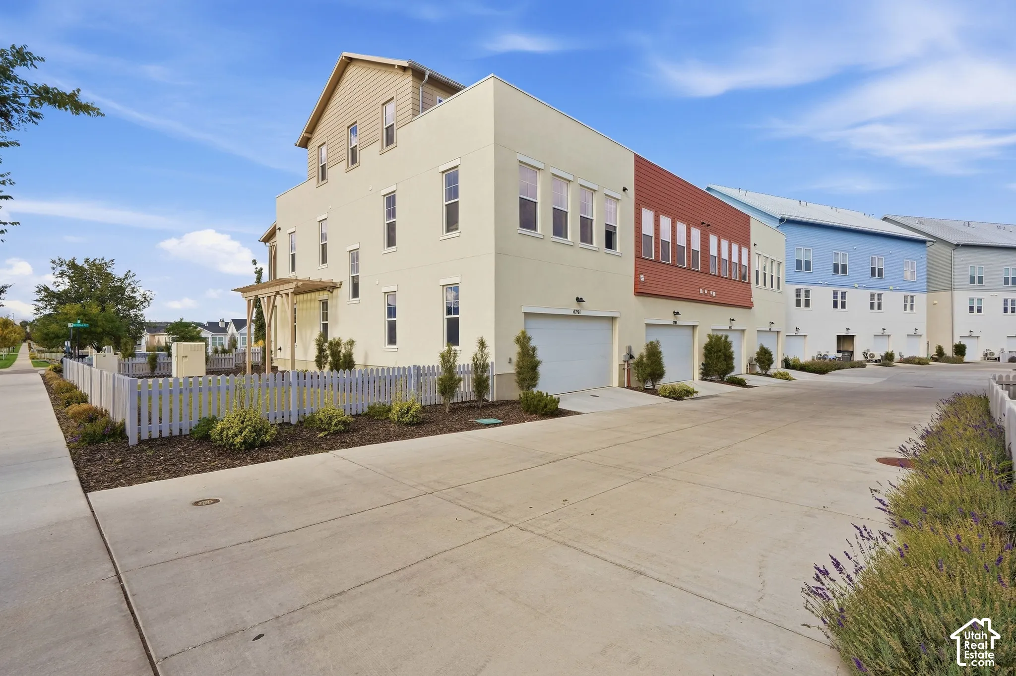 Multi-level exterior with stucco and siding elements, featuring multiple windows, a private fenced yard, and an integrated garage