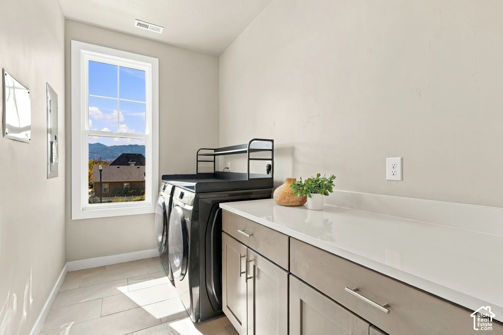 Laundry space with light wood-finish cabinetry, white countertop, and tile flooring