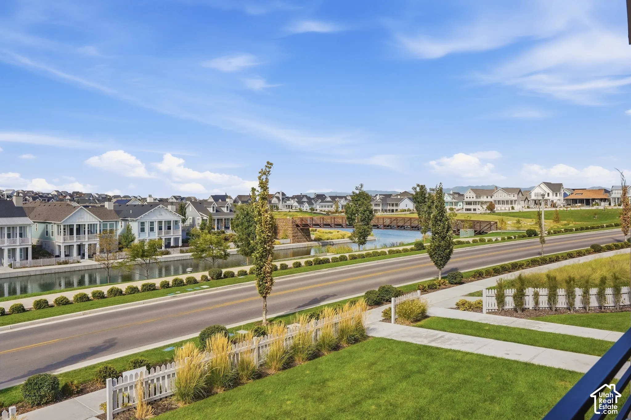 Manicured lawn with a white picket fence, concrete sidewalk, and established landscaping