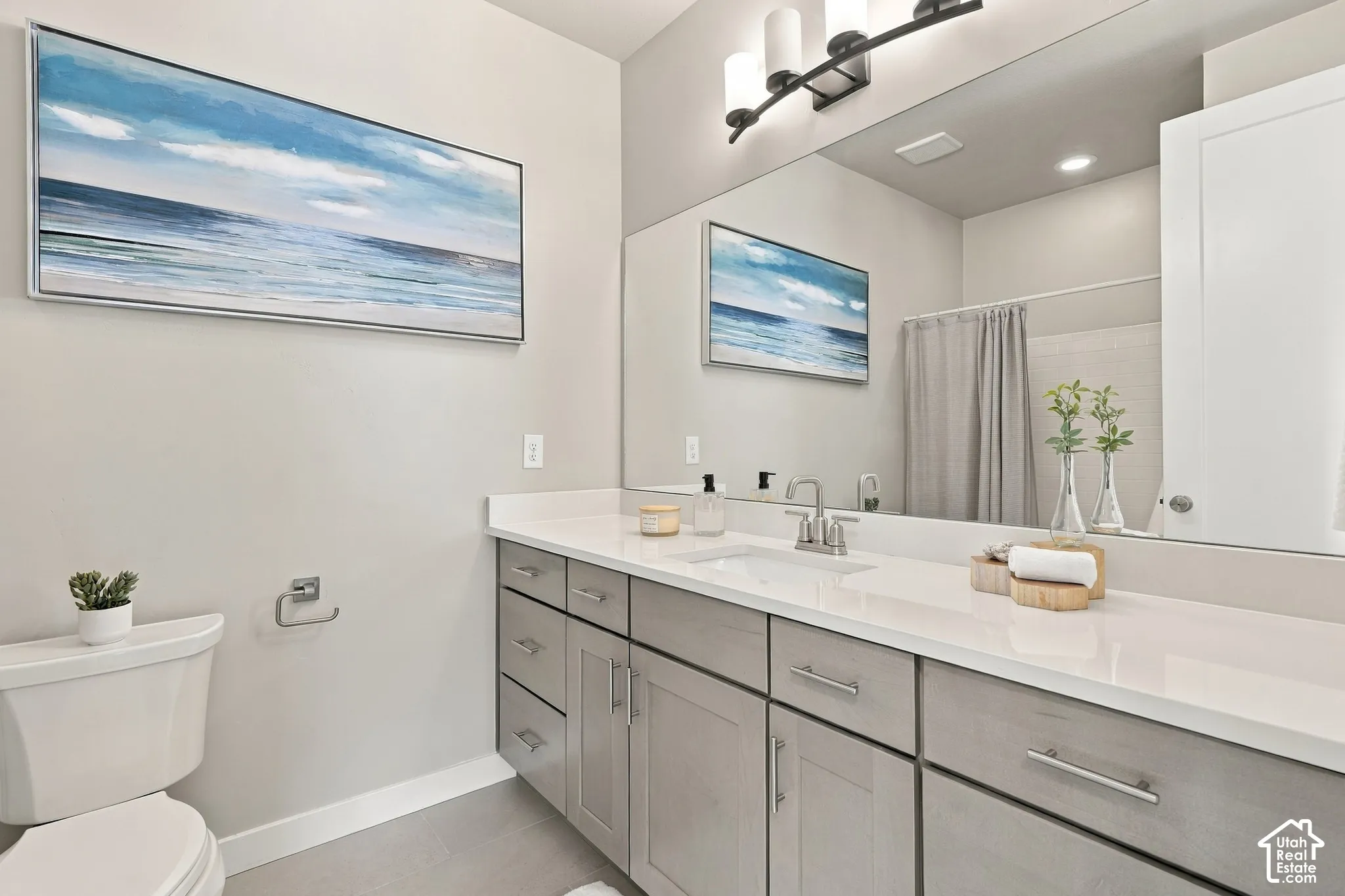 Extended vanity with light-toned countertop, dual-tone cabinetry, and an integrated sink