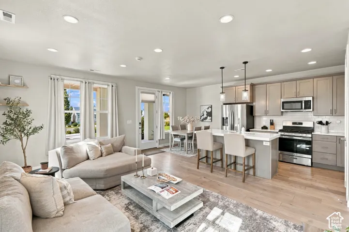 Open-concept living space featuring wood-finish flooring, recessed lighting, and a kitchen with stainless steel appliances
