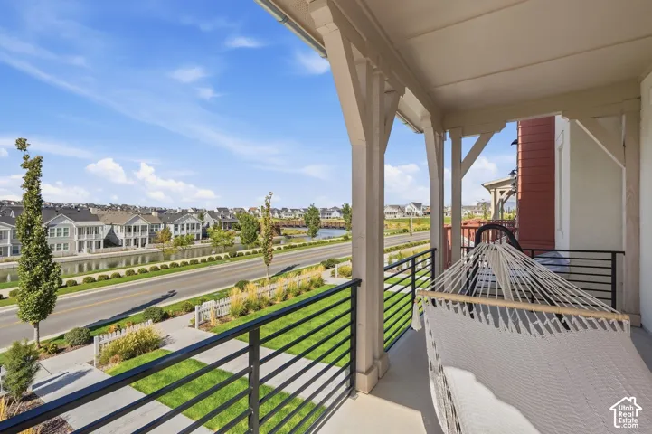 Covered balcony with a concrete floor, black horizontal railings, and exposed beam ceiling