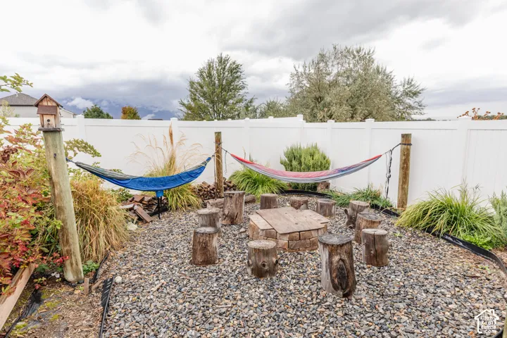 Privacy fencing with gravel ground cover, featuring a built-in fire pit and tree stump seating