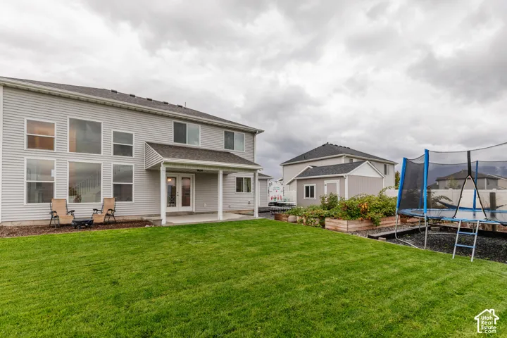 Expansive backyard featuring a manicured lawn, covered patio, raised garden beds, and a detached storage shed