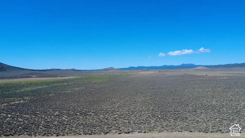 Expansive land parcel featuring natural shrubland and distant mountain ranges