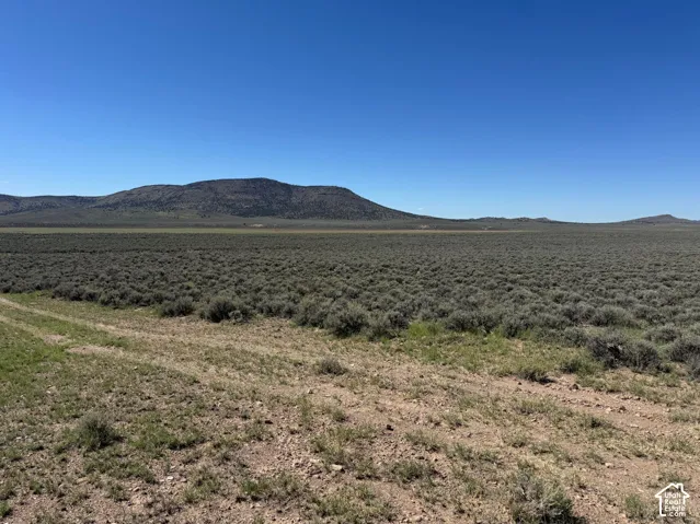 Expansive open terrain with natural vegetation, distant mountains, and clear blue sky