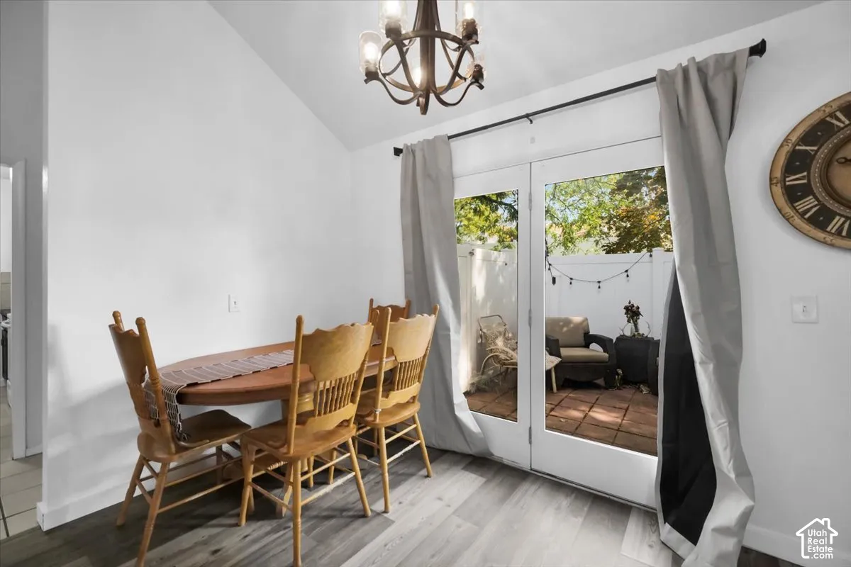 Dining area with wood-finish flooring, chandelier lighting, and French doors opening to a private outdoor patio