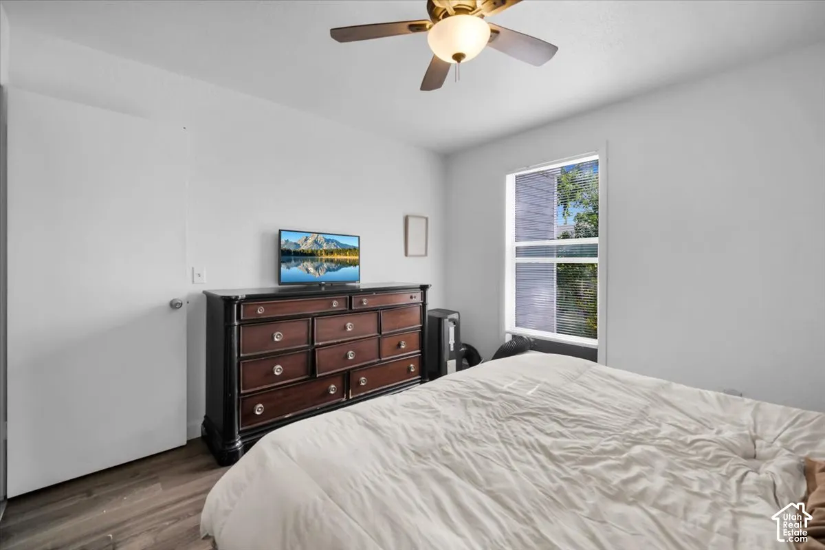 Wood-finish flooring, white walls, and a ceiling fan with integrated lighting