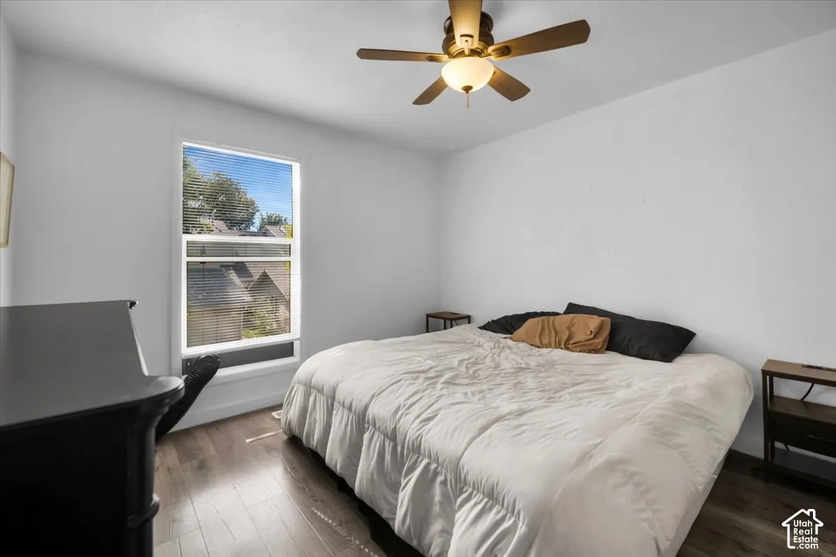 Wood-finish flooring, ceiling fan with integrated lighting, and a window with blinds