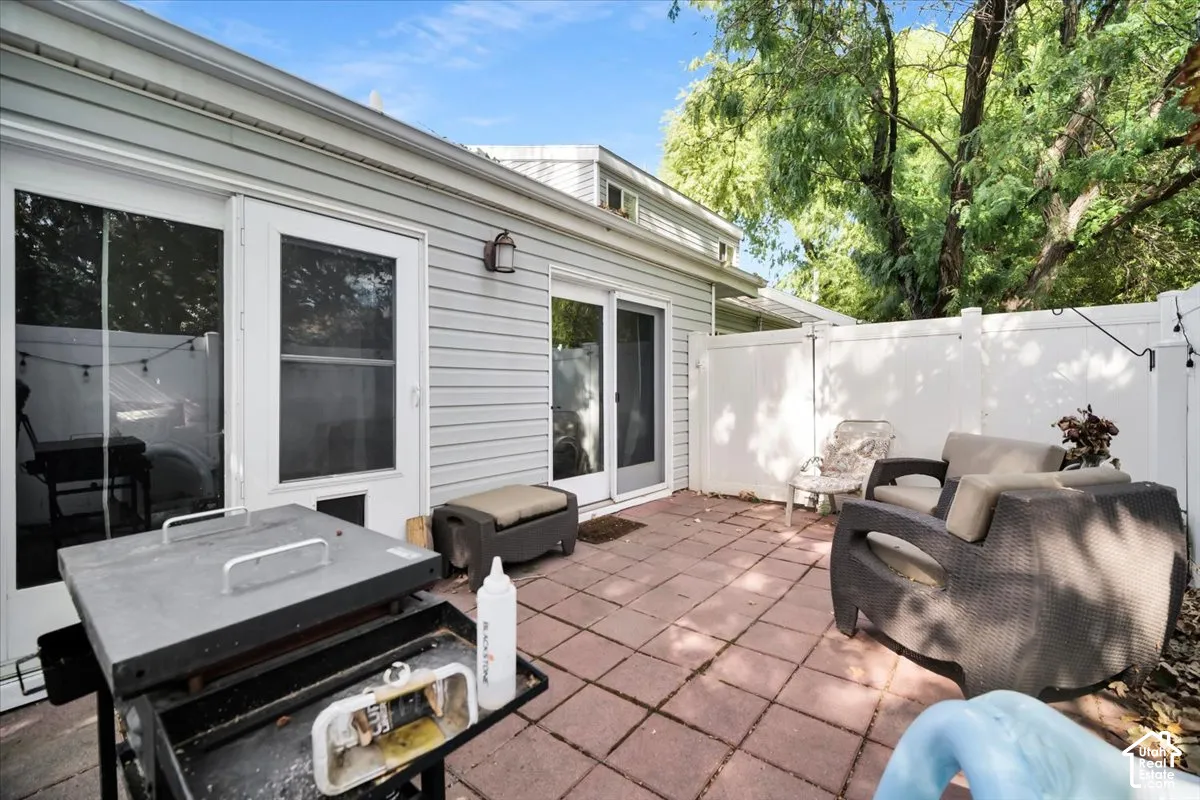 Private patio featuring brick pavers, white privacy fencing, and direct access to interior spaces via a sliding glass door and a secondary full-light door