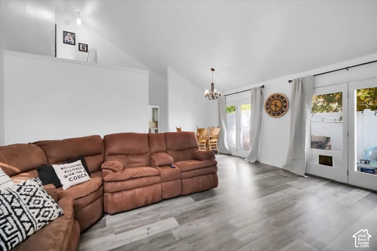 Vaulted ceilings with recessed lighting, wood-finish flooring, and multiple glass doors providing outdoor access