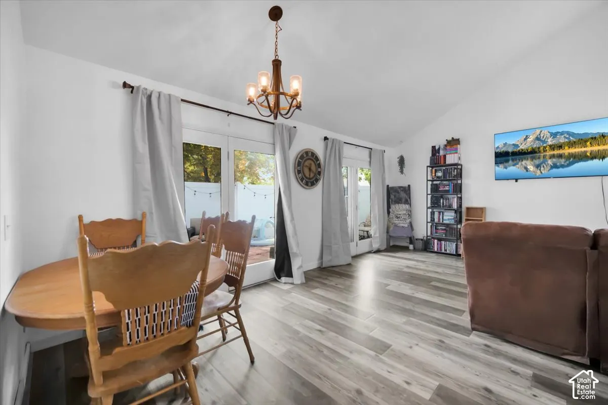 Vaulted ceiling, wood-finish flooring, two sets of glass doors, and a decorative chandelier