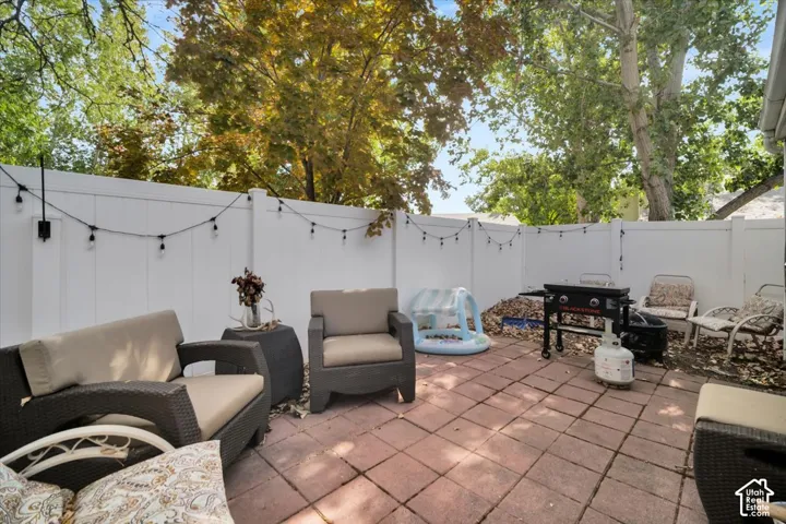 Patio featuring paver flooring, white privacy fencing, and string lighting