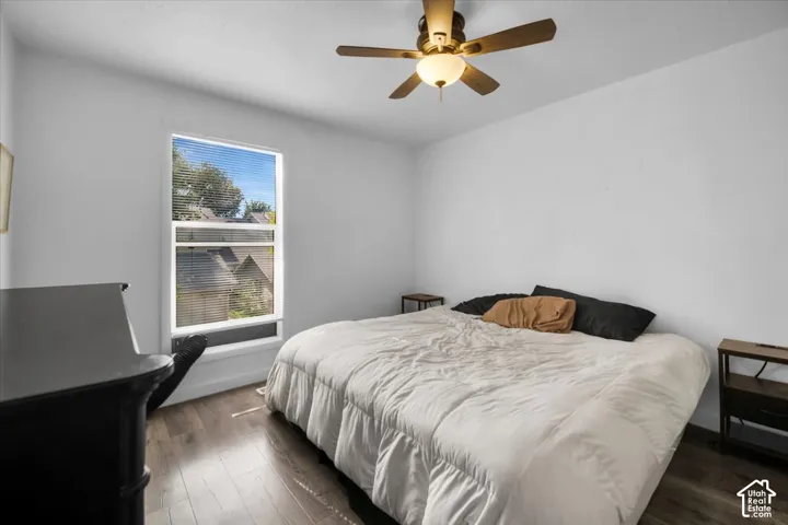 Wood-finish flooring, ceiling fan with integrated lighting, and a window with blinds