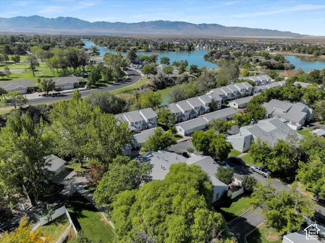 Aerial perspective showcasing a residential community with a large body of water, extensive green spaces, and mountain scenery