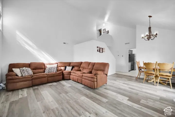 Vaulted ceilings, wood-finish flooring, staircase, and a chandelier