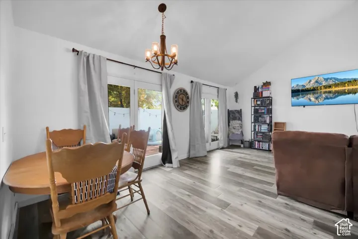 Vaulted ceiling, wood-finish flooring, two sets of glass doors, and a decorative chandelier